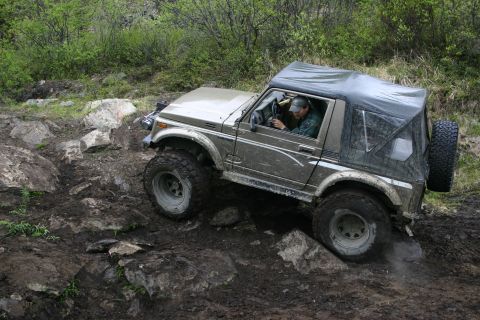 2003 Jeep TJ - A driver maneuvers a Suzuki Samurai over challenging off-road terrain.