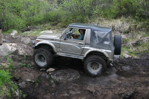 2003 Jeep TJ - A tan Suzuki Samurai navigates a challenging rocky and muddy off-road course.
