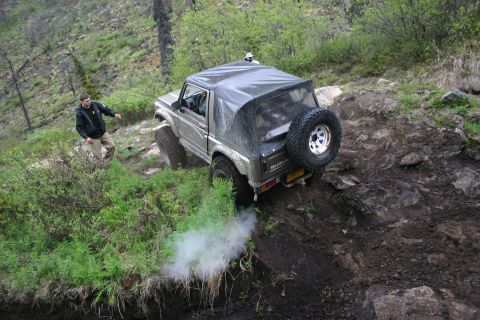 2003 Jeep TJ - A Suzuki Samurai navigates a challenging off-road course, kicking up dust and smoke.