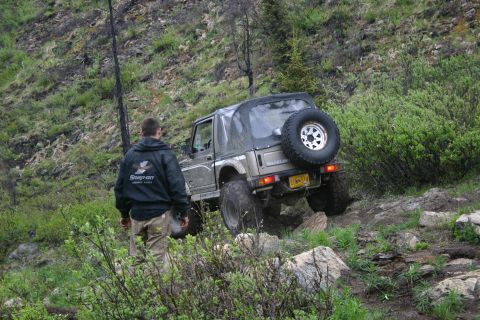 2003 Jeep TJ - A Suzuki Samurai navigates a challenging off-road path with dense foliage and rocky terrain.