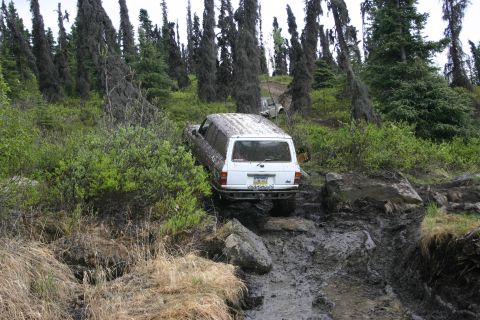 2003 Jeep TJ - This white SUV is tackling a challenging off-road trail, with another vehicle visible in the background.