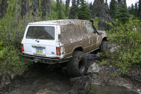 2003 Jeep TJ - This heavily mud-covered SUV navigates a challenging rocky and muddy off-road course.