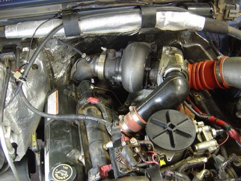 1986 Ford Bronco II - Close-up of an engine bay, focusing on the turbocharger and associated plumbing. Some text is visible on labels.