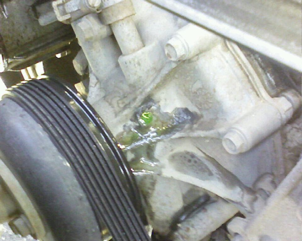 Engine part leaking green fluid near ribbed pulley