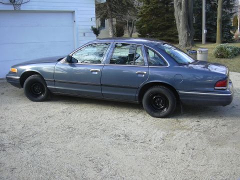 1996 Ford Crown Victoria - A blue sedan is parked on a gravel driveway in front of a white garage.
