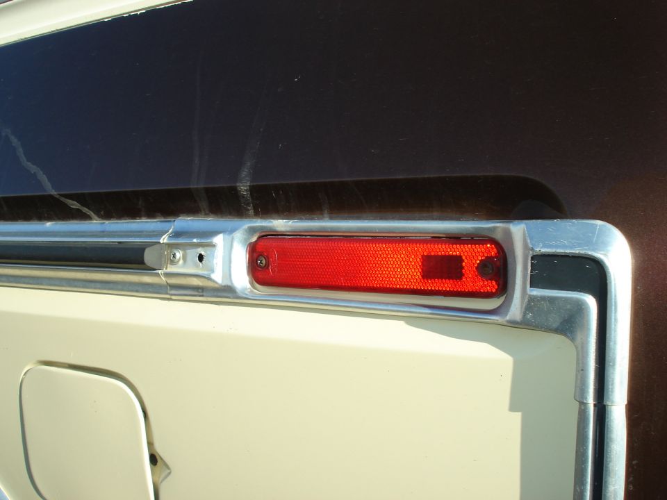 Close-up of a red rectangular marker light with chrome trim on a vehicle