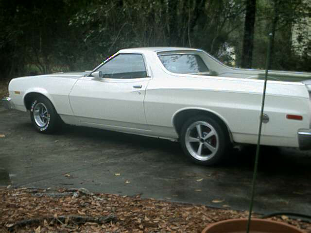 White 1970s Ford Ranchero side view on driveway with mismatched front and rear wheels