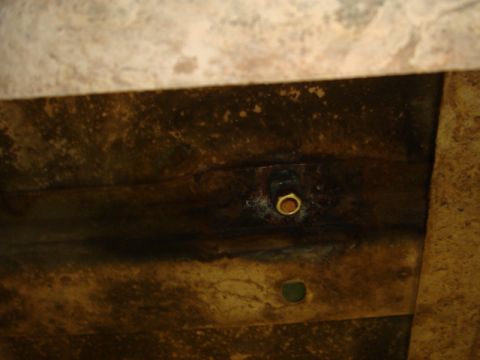1996 Ford Bronco - A close-up view of the underside of a vehicle's frame, showing a bolt and a hole.