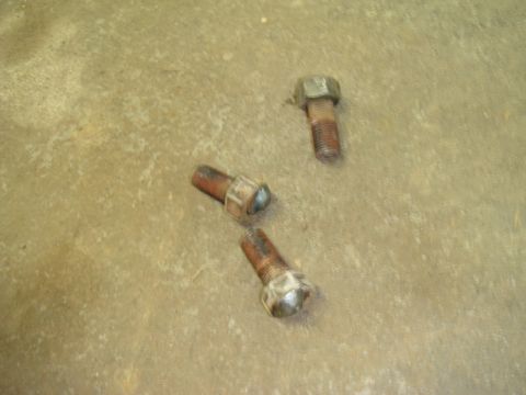 1996 Ford Bronco - Three rusty bolts lie on a concrete floor, possibly related to a vehicle repair or build.