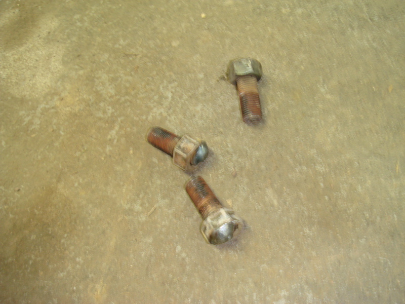 Three rusty bolts on a concrete surface