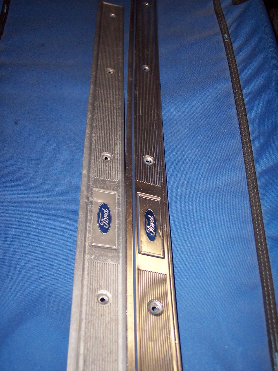 Two Ford door sill plates on blue fabric, one dull and oxidized, one polished bright
