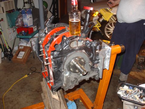 1986 Mazda RX-7 - A rotary engine is mounted on an engine stand in a garage setting, with a beer bottle precariously balanced on its housing.