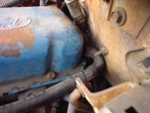 1977 Ford Bronco - Close-up of a Ford valve cover in an engine bay, showing engine components and hoses.