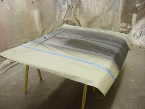1991 Ford Bronco - A car hood is covered in masking paper and tape, resting on sawhorses in a workshop.