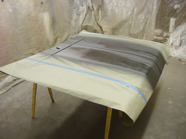 Car hood on sawhorses, covered in masking paper and tape, ready for paint prep