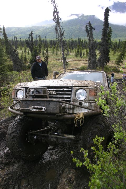 2003 Jeep TJ - A heavily mud-splattered Toyota Land Cruiser FJ60 navigates a challenging off-road course.