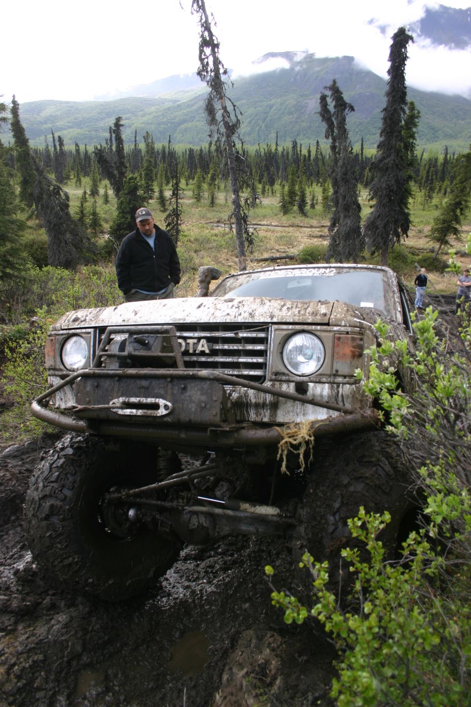Mud-covered Toyota Land Cruiser FJ60 with winch, off-roading in a forest