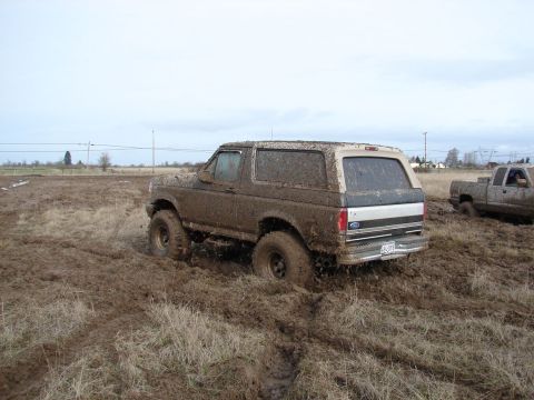 1996 Ford Bronco - A Ford Bronco navigates a challenging muddy terrain, with another vehicle visible in the background.