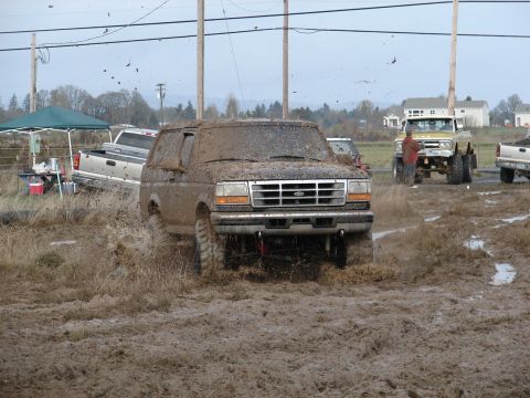 1996 Ford Bronco - This 1996 Ford Bronco is navigating a challenging muddy terrain, kicking up mud as it goes.