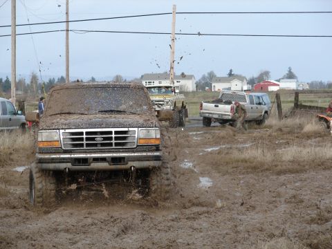 1996 Ford Bronco - A 1996 Ford Bronco navigates a challenging muddy terrain, with other vehicles visible in the background.