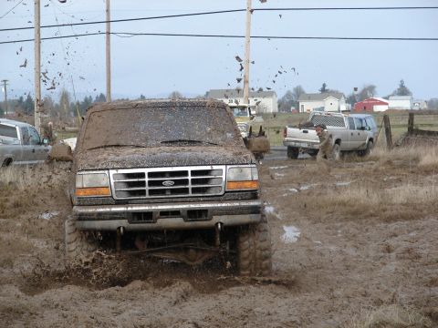 1996 Ford Bronco - This Ford truck is stuck in the mud, with other vehicles in the background.