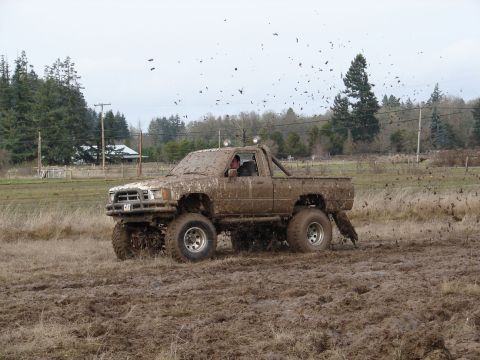 1996 Ford Bronco - This heavily modified pickup truck is covered in mud as it navigates a challenging off-road course.