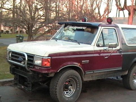 1990 Ford Bronco - This two-tone Ford Bronco features a prominent brush guard and auxiliary lights on the roof visor.