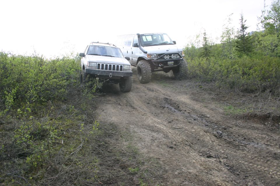 1997 Jeep Grand Cherokee and a modified van on a muddy trail