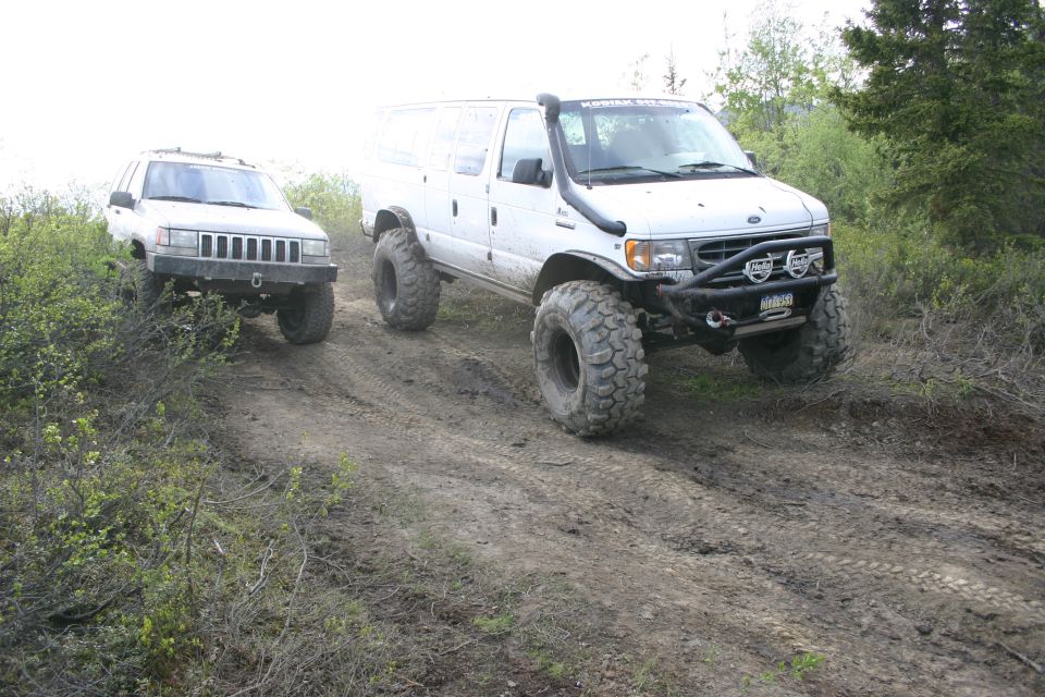 White van and silver SUV on a muddy trail