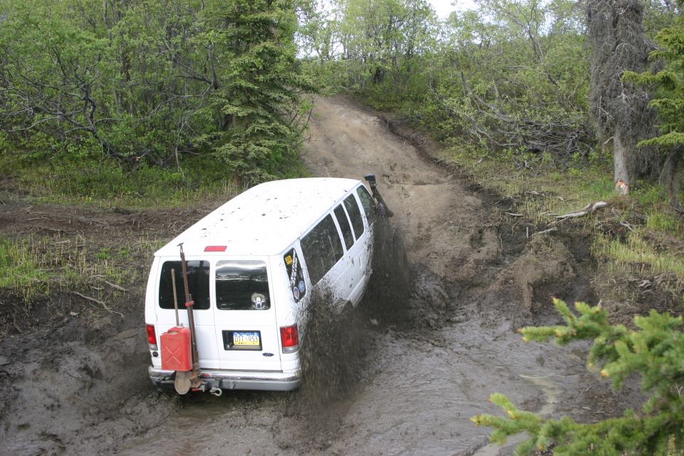 White van struggling in mud on off-road trail