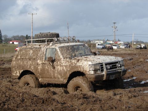 1996 Ford Bronco - This 1996 Ford Bronco is deep in mud, showing off its off-road capabilities.