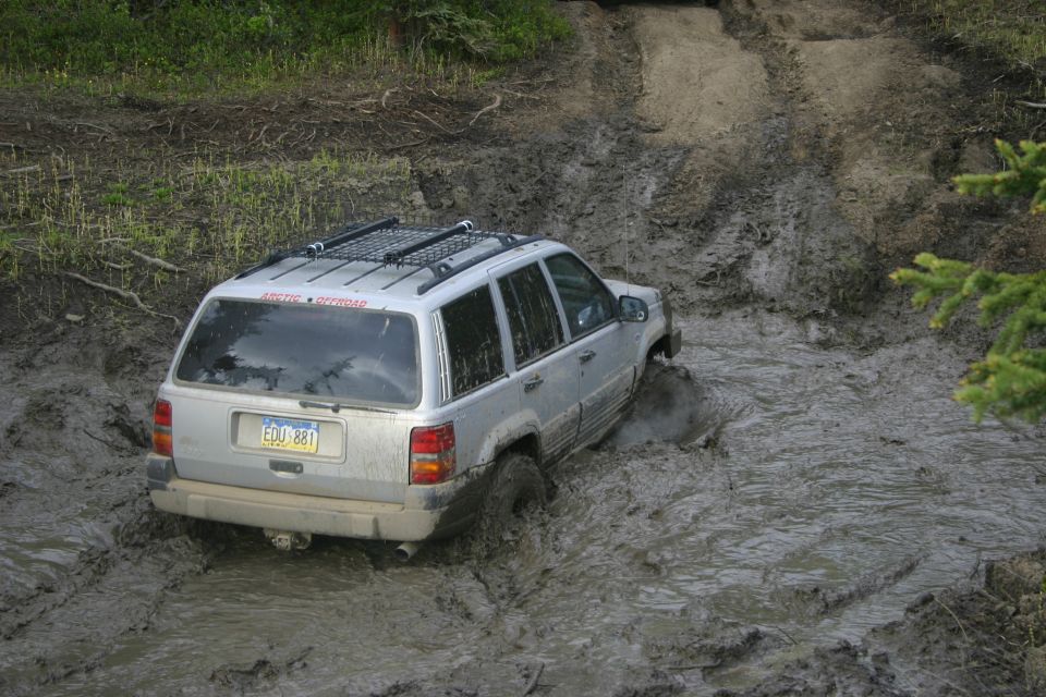 Silver Jeep Grand Cherokee navigating a muddy trail, license plate EDU 881