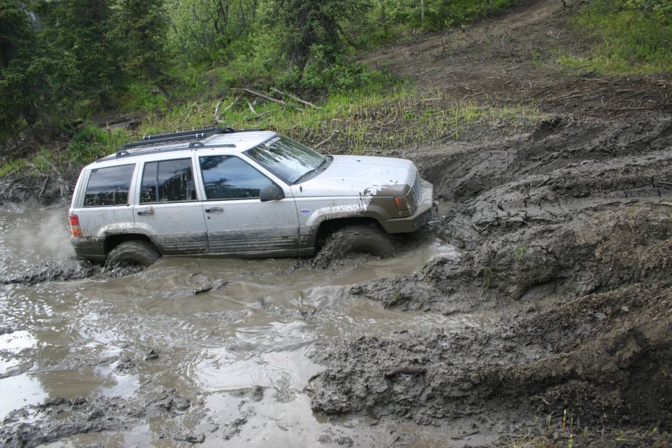 Silver 1999 Jeep Grand Cherokee stuck in deep mud
