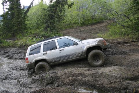 2003 Jeep TJ - A Jeep Grand Cherokee navigates a challenging muddy terrain during an off-road excursion.