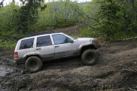 2003 Jeep TJ - A silver SUV navigates a challenging muddy off-road course.