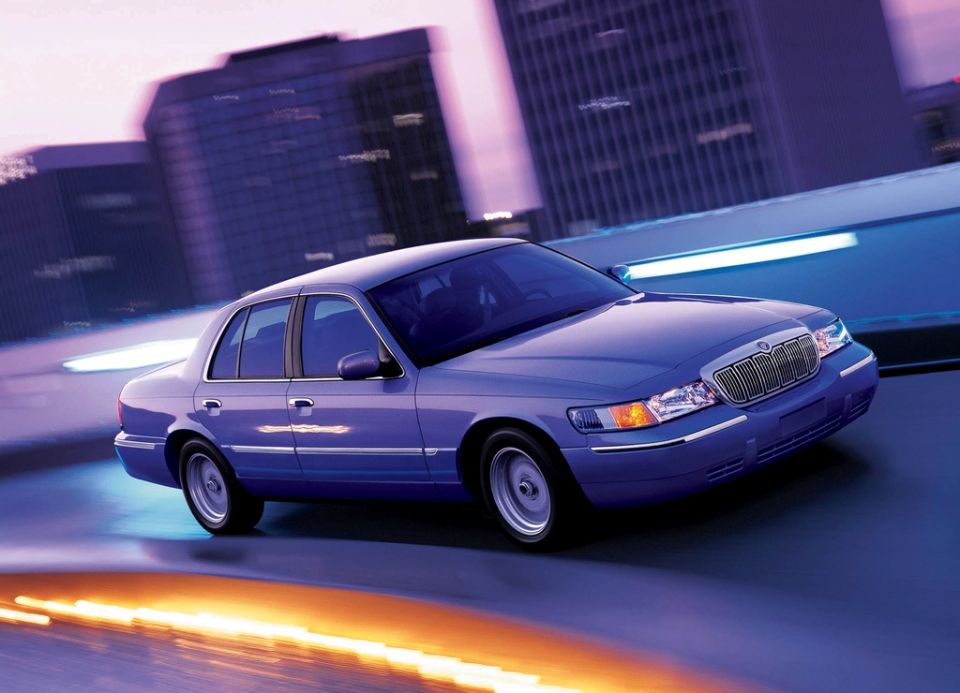 Purple-blue Mercury Grand Marquis sedan front three-quarter on a city street at night