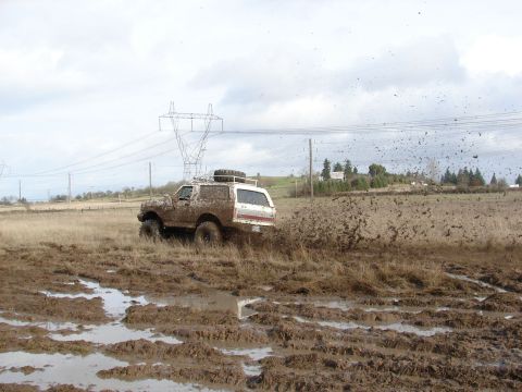 1996 Ford Bronco - Ford Bronco navigating a challenging muddy terrain under an overcast sky.