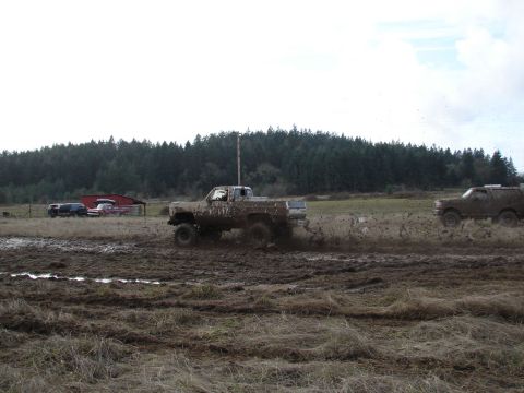 1996 Ford Bronco - A muddy pickup truck navigates a challenging off-road course, with other vehicles visible in the background.