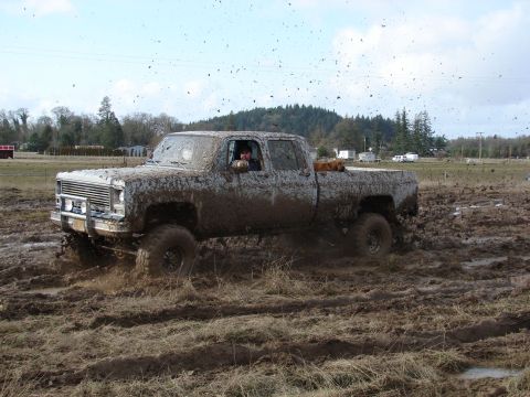 1996 Ford Bronco - Pickup truck navigating a muddy terrain, with mud splattering everywhere.