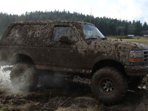 1996 Ford Bronco - This 1996 Ford Bronco is heavily covered in mud as it navigates a muddy terrain.