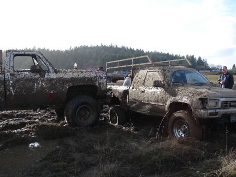 1996 Ford Bronco - Two pickup trucks are stuck in the mud during an off-roading event.