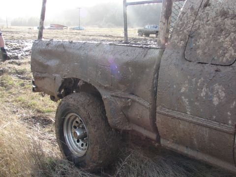1996 Ford Bronco - A heavily mud-splattered pickup truck is seen from the side, with another truck visible in the background.