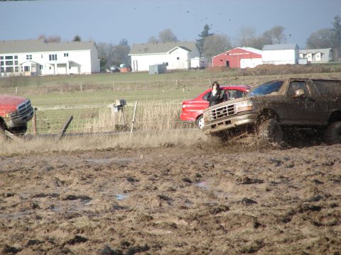 1996 Ford Bronco - This SUV, likely from the early to mid-1990s, navigates a challenging muddy terrain with another vehicle in the background.