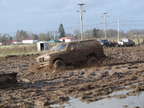 1996 Ford Bronco - Ford Bronco navigating a challenging mud bog with other vehicles nearby.