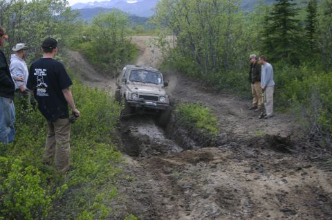2003 Jeep TJ - An off-road vehicle tackles a challenging muddy trail during an outdoor event.