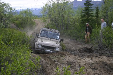 2003 Jeep TJ - A Suzuki Samurai navigates a muddy off-road trail, kicking up dirt as it gets stuck.