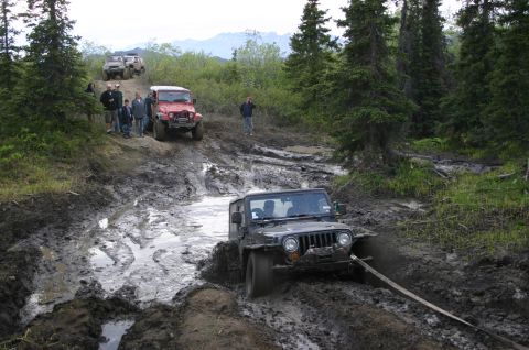 2003 Jeep TJ - Multiple Jeeps tackle a challenging muddy trail during an off-road event.