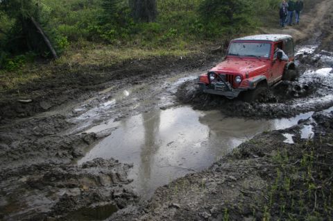 2003 Jeep TJ - A red 2003 Jeep TJ Wrangler tackles a challenging mud pit during an off-road event.