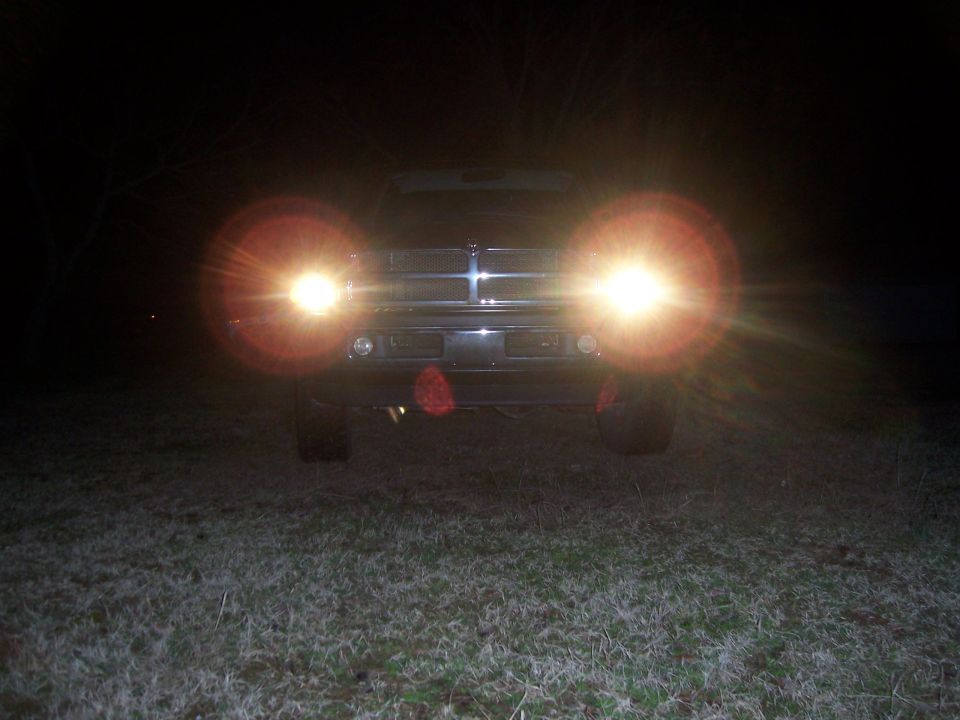 Dodge Ram pickup at night on frosty grass, headlights flaring at the camera