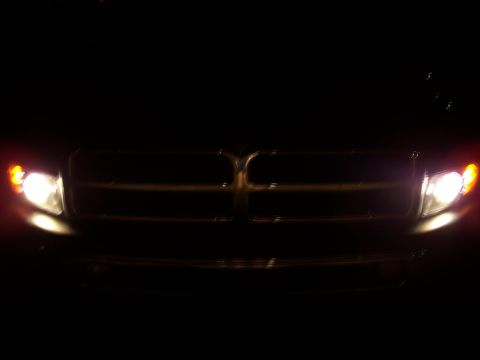 2001 Dodge 1500 - The distinctive crosshair grille and headlights of a 2001 Dodge 1500 are illuminated against the dark.